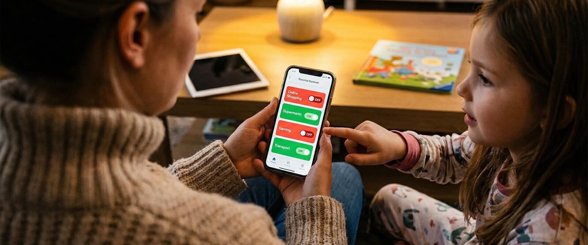 Mutter zeigt ihrer 8-jährigen Tochter die Kategoriesperren einer Taschengeld-App: Online Shopping und Gaming sind deaktiviert, Supermarkt und Transport erlaubt