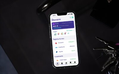 Finanzguru-App auf einem Smartphone neben Schlüsselbund und Geldbörse (Bild: Finanzguru)
